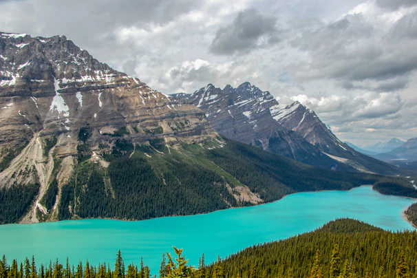 A breathtaking view of snow-capped mountains, turquoise lake, and a glacier under a clear sky.
