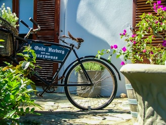 A vintage bicycle leaning against a cream-colored villa wall, adorned with fresh lavender bouquets.