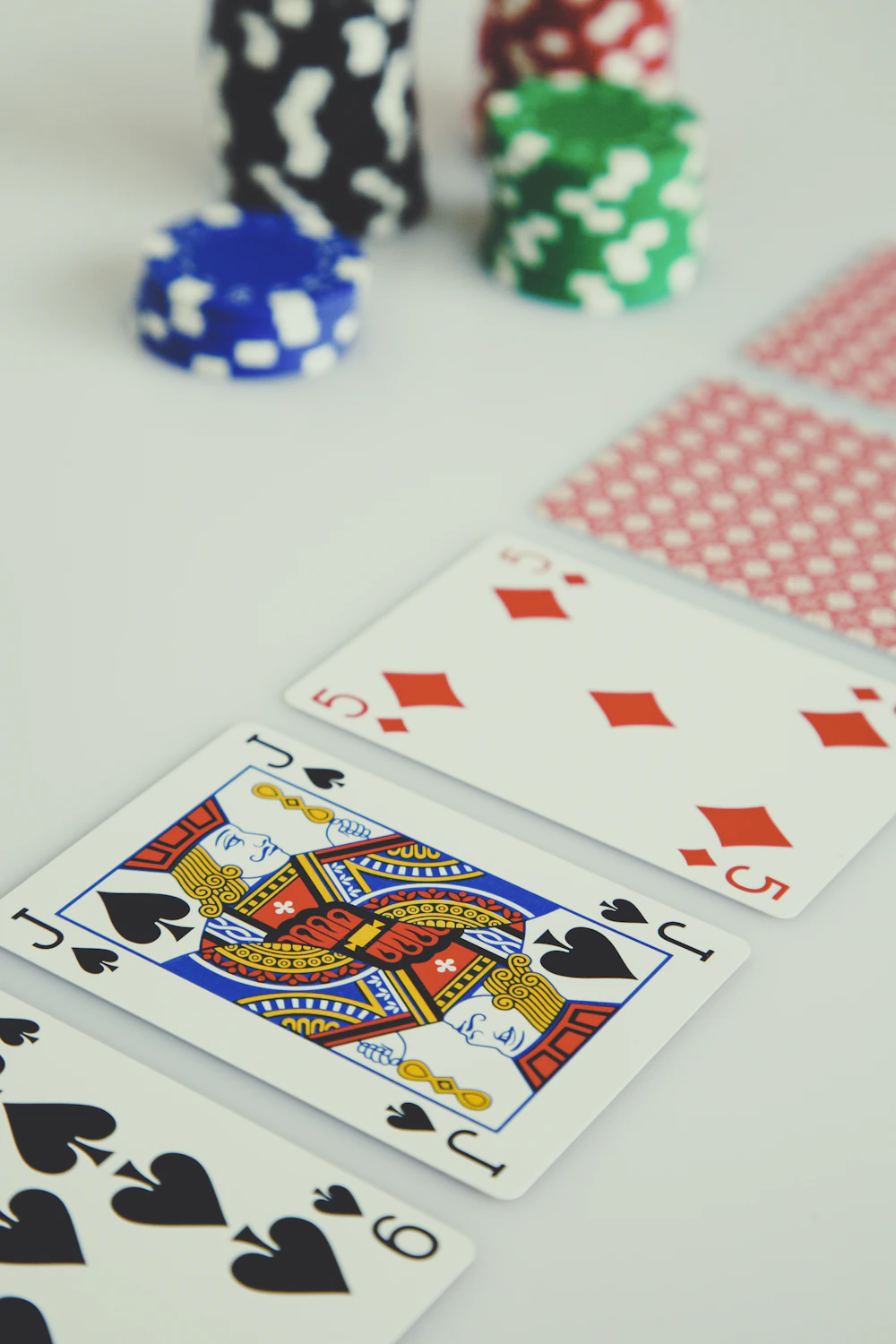 Playing cards and colorful poker chips on a white table