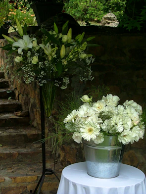 Elegant wedding floral arrangement with white lilies and greenery in a rustic venue