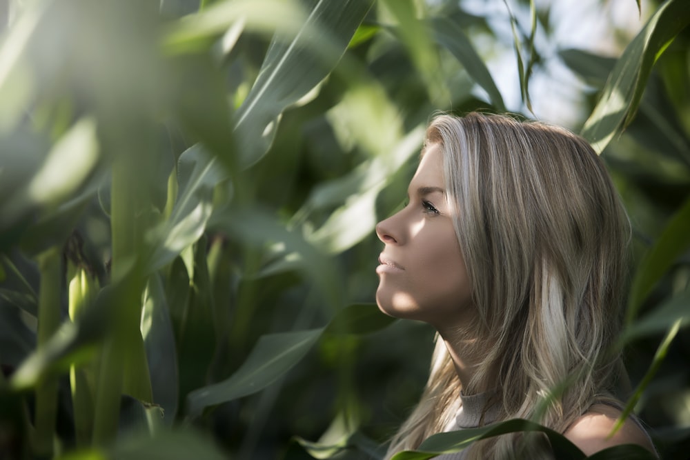 woman standing surrounded with green leaves