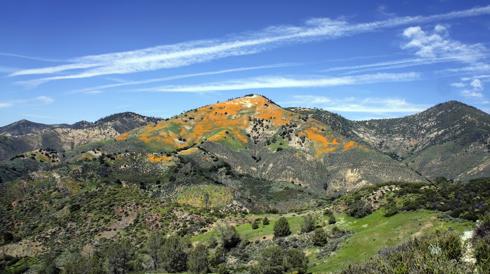 brown and green mountain under white clouds and blue sky