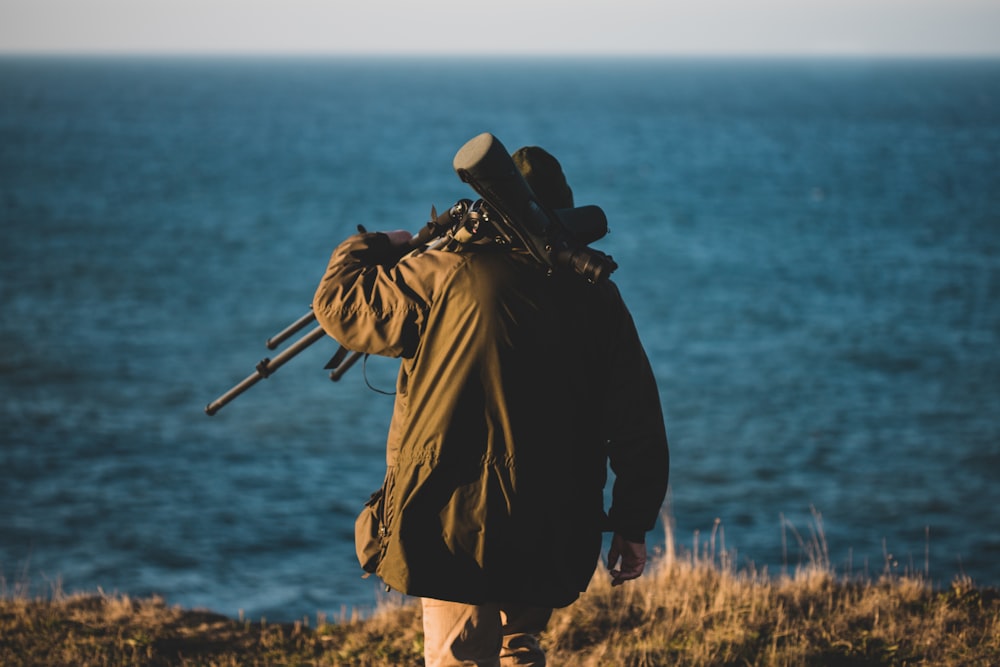 man wearing black jacket walking near the ocean