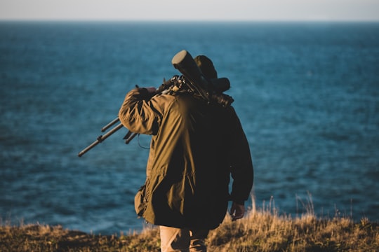 man wearing black jacket walking near the ocean in Sheringham United Kingdom