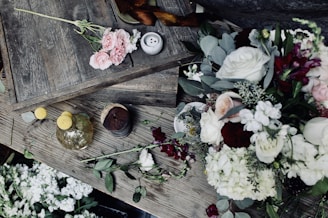 Seasonal flowers in soft pinks and whites displayed on a rustic wooden table.