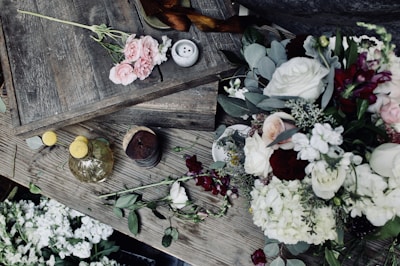 Seasonal flowers in soft pinks and whites displayed on a rustic wooden table.
