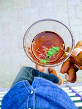 Close-up of hands holding a cup of herbal tea on a white and blue background.