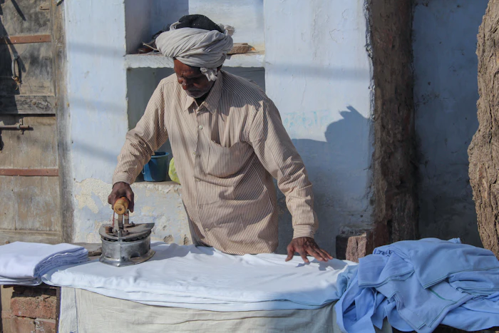 Elderly Indian man ironing clothes