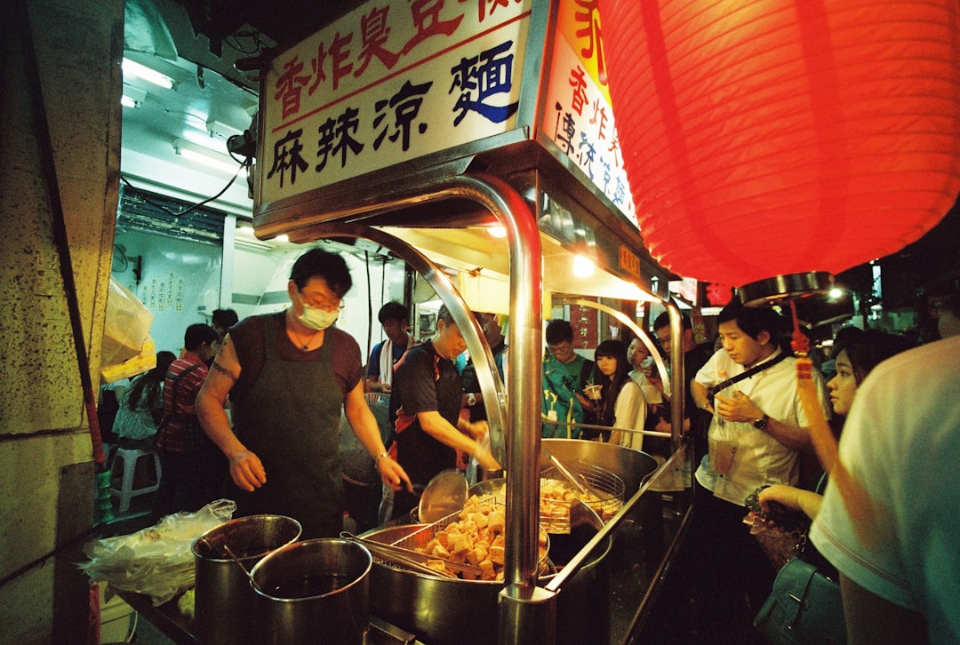 man wearing black apron and mask cooking food in street food area