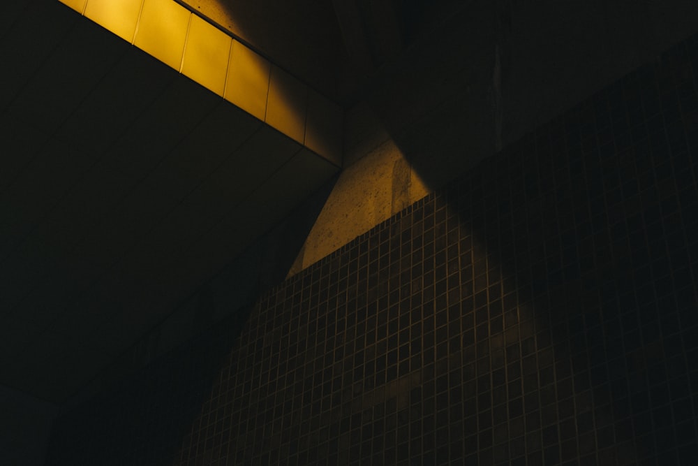 a yellow light shines on a tiled wall