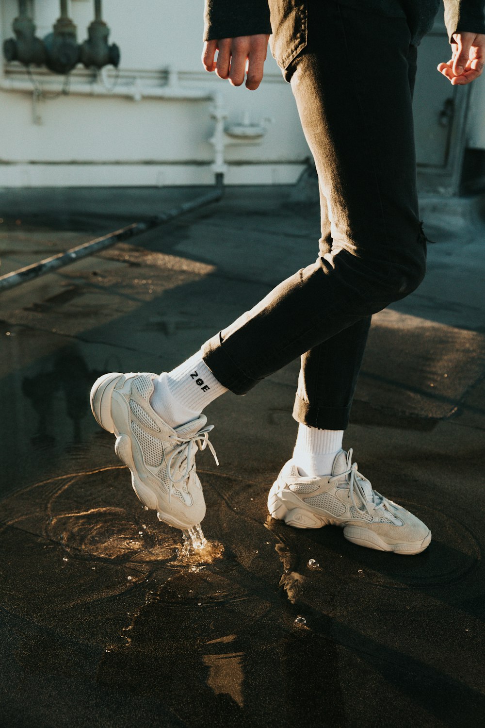 person wearing black long-sleeved shirt, black pants and white lace-up sneakers outfit