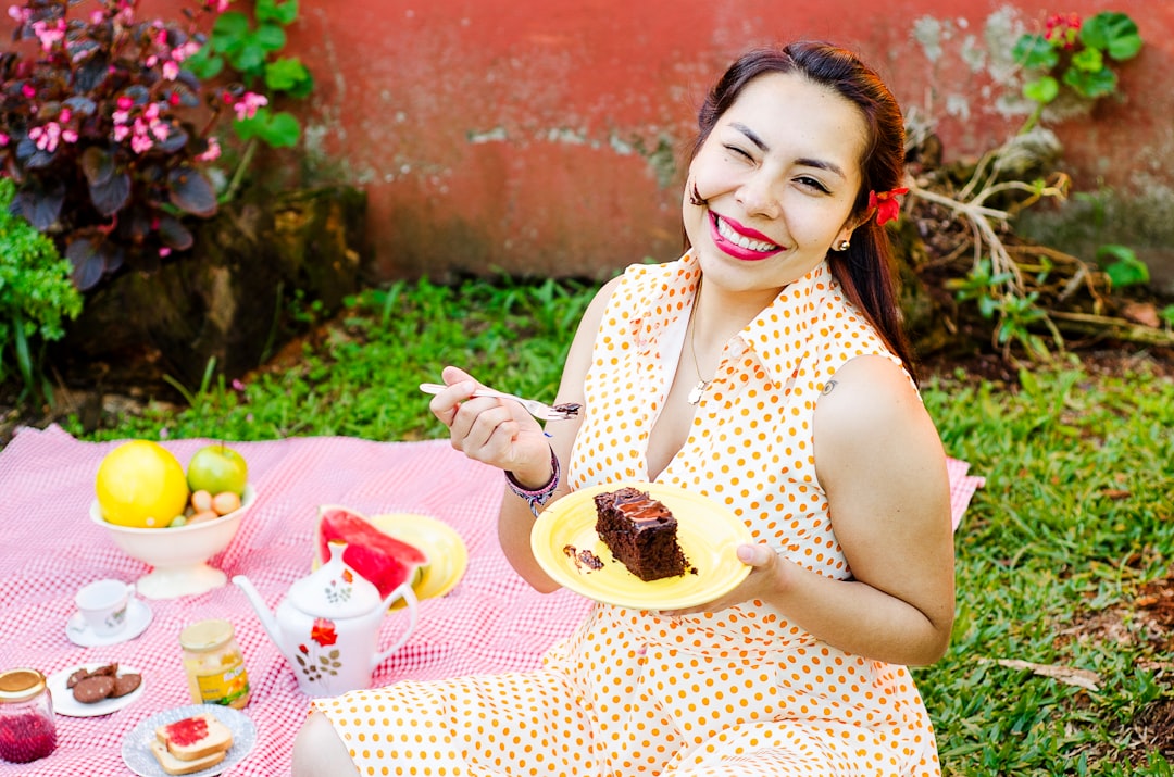 woman in polka-dot dress holding fork and plate with slice of cake