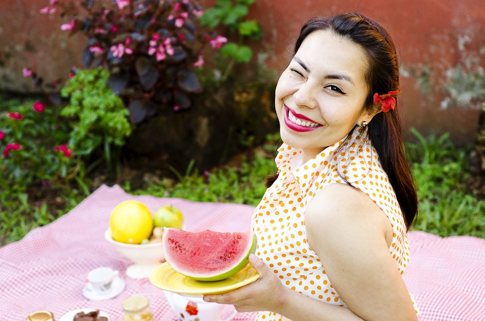 woman holding plate of sliced watermelon