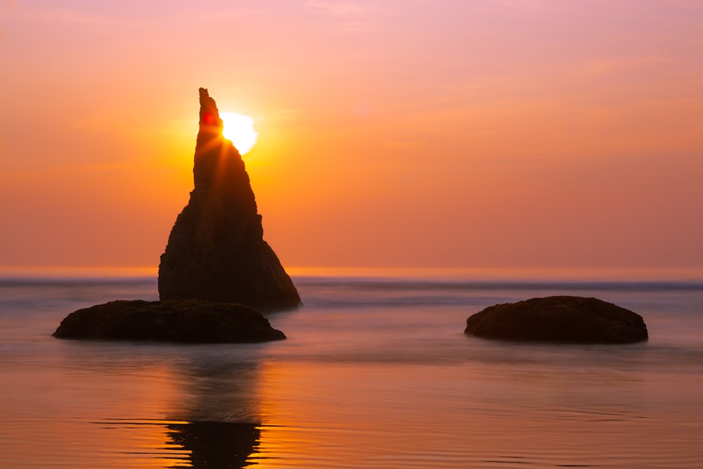 rock formation in body of water during golden hour