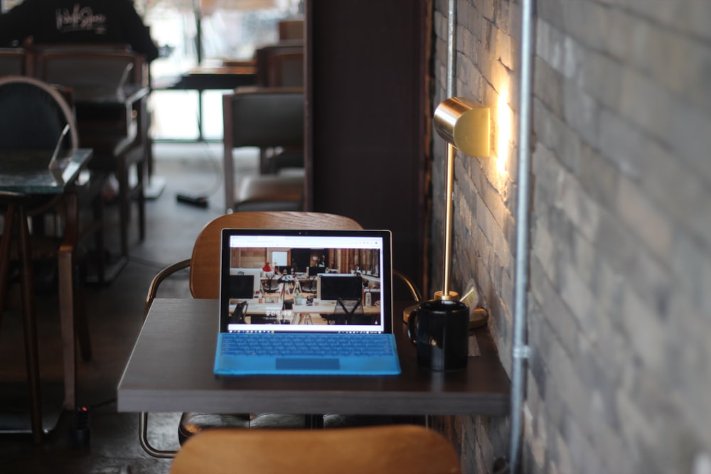 turned-on blue-and-black laptop computer on table near black ceramic mug