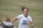 A female soccer player wearing a white jersey with 'Hoyas' and the number 23 printed on it is captured mid-motion, smiling with hair flying back. She appears to be on a grass field, engaging with someone in the foreground who wears a jacket with a fur collar.