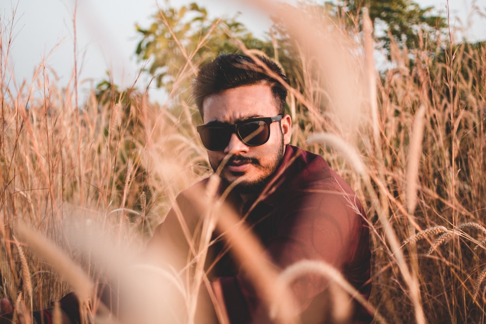 man surrounded by brown grass during daytime