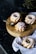 Four small bundt cakes with white icing are arranged on a wooden round board. One of the cakes is decorated with red berries. A small silver spoon is placed on the board. A light blue napkin is draped underneath the board and one cake rests on it.