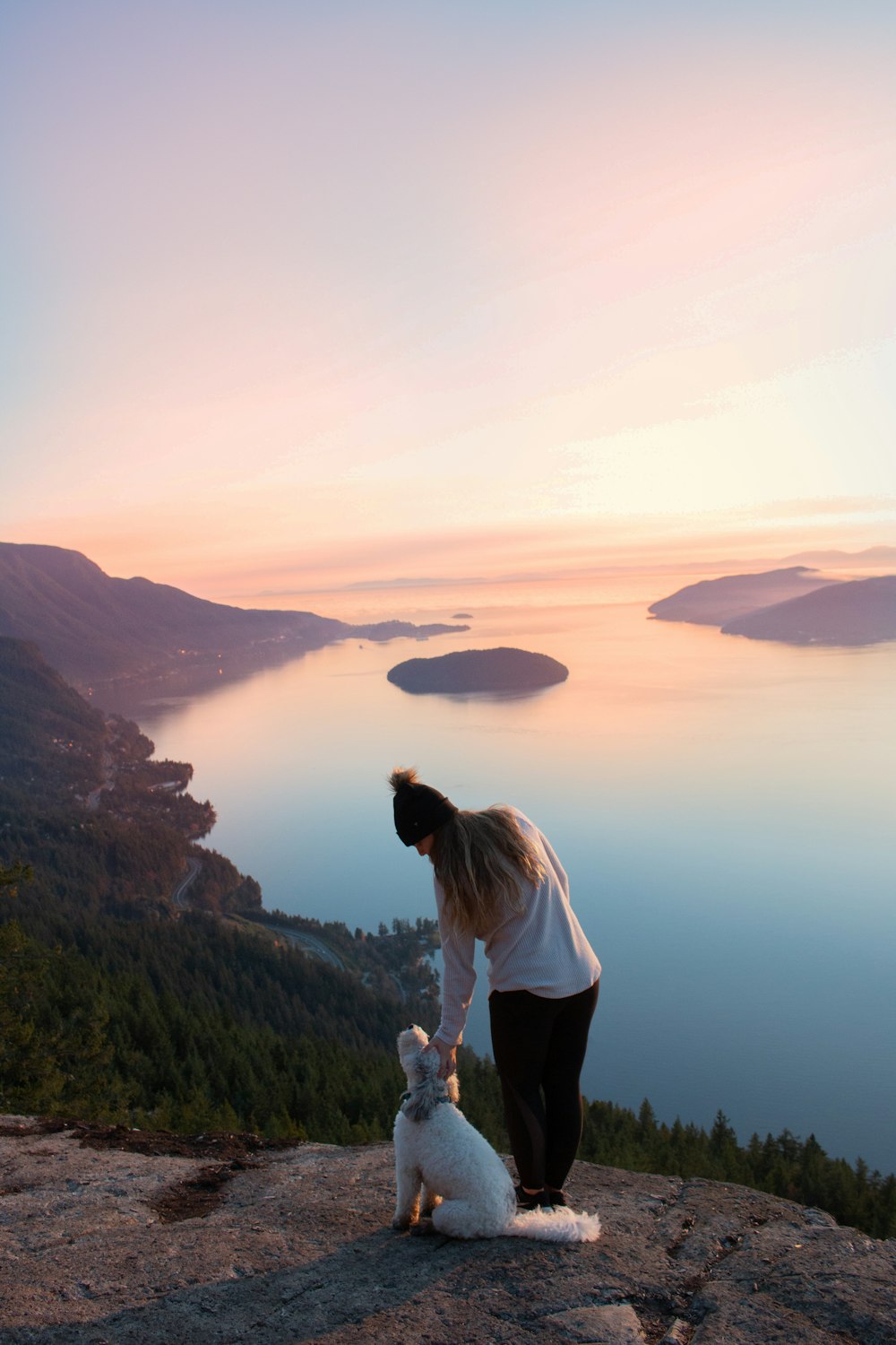 woman standing beside dog near the body of water