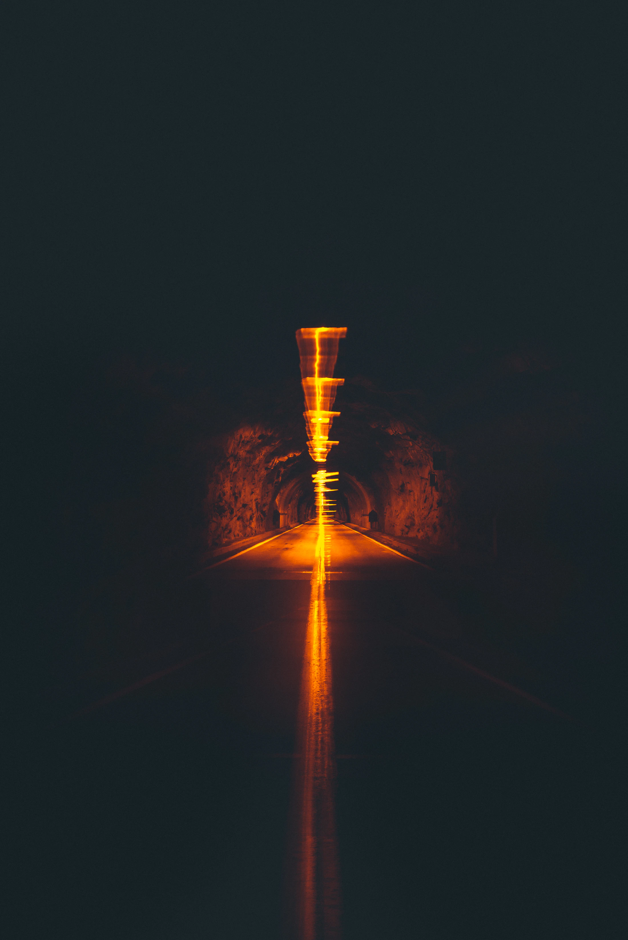 Galerie souterraine parcourue par un éclairage orange intense.
