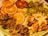 A plate filled with a colorful array of dried fruits, including orange slices, apple chips, kiwi slices, figs, banana chips, and sweet potato slices, all arranged in an appealing manner.