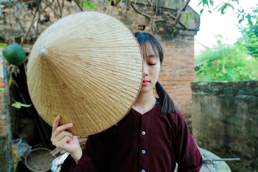 woman closing her eyes while holding straw hat