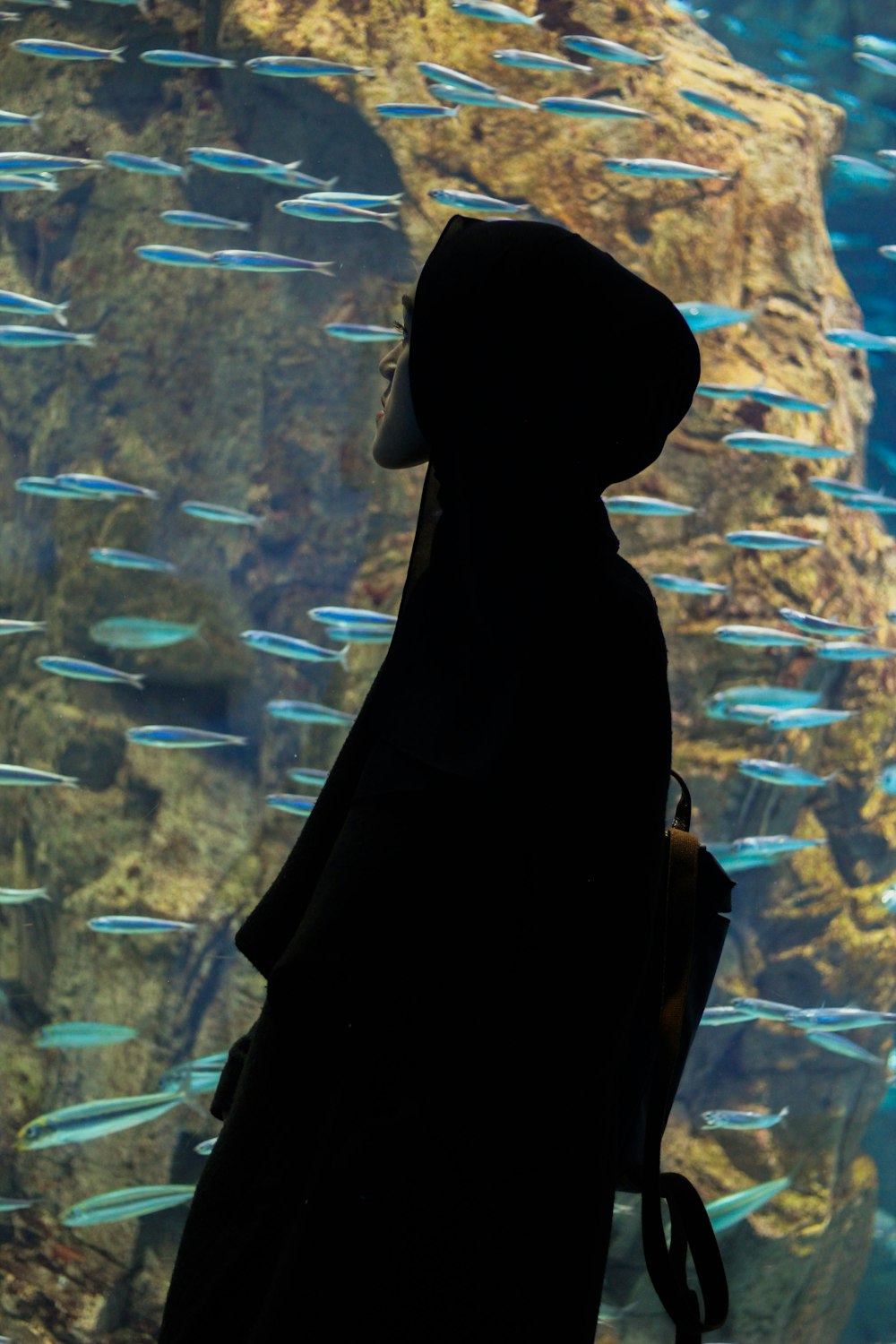 man in a hooded jacket by an aquarium
