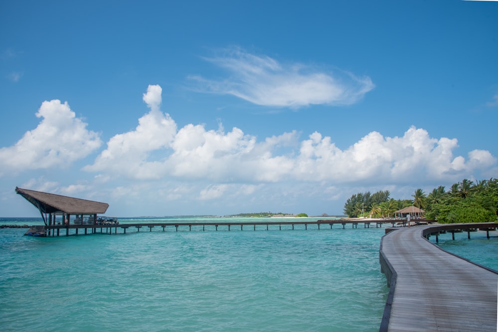 wooden bridge on-top of water with cottage during daytime \