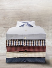 Photo of a neatly arranged set of corporate uniforms with embroidered logos on a wooden table.