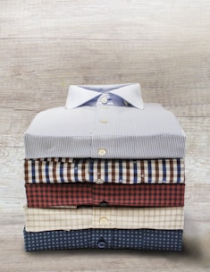 A neatly folded stack of freshly pressed clothes on a wooden table.