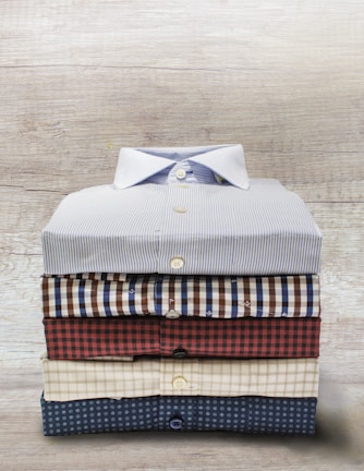 A navy blue casual button-down shirt neatly folded on a wooden table.