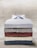 A neatly stacked set of five folded button-up shirts, each with different patterns and colors, arranged on a wooden surface.