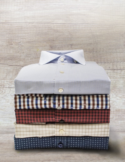A close-up of a neatly folded stack of trendy shirts in various patterns.