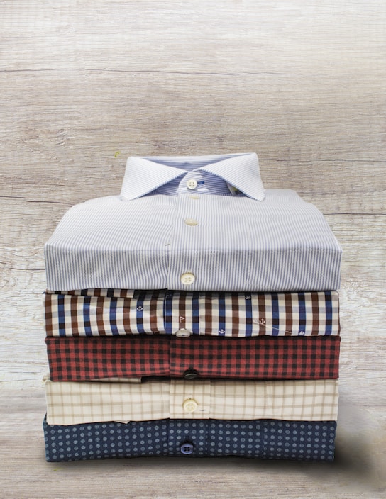 Close-up of neatly folded institutional uniforms stacked on a wooden table.