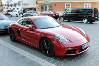 A sleek red compact car parked on a sunny Spanish street with traditional buildings in the background.