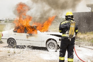 firefighter fighting burning car