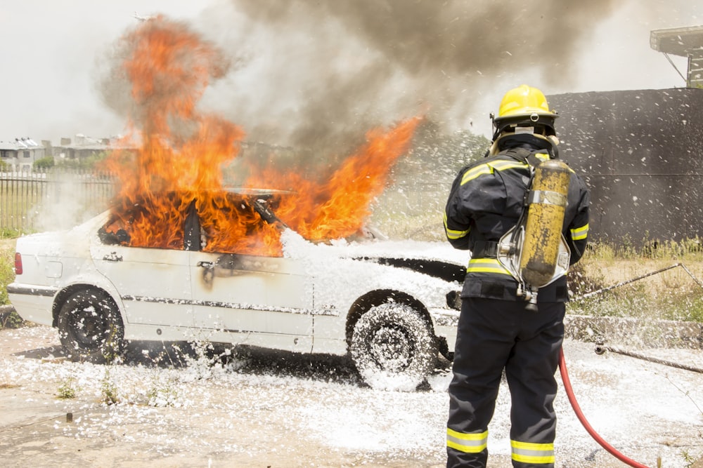 firefighter fighting burning car