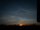 The peaceful skyline at dusk with silhouettes of tall trees around the property.