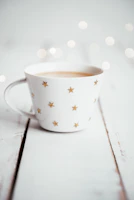 Close-up of a beige ceramic mug with a delicate golden print on a white background