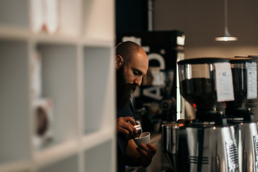 man pouring coffee on teacup