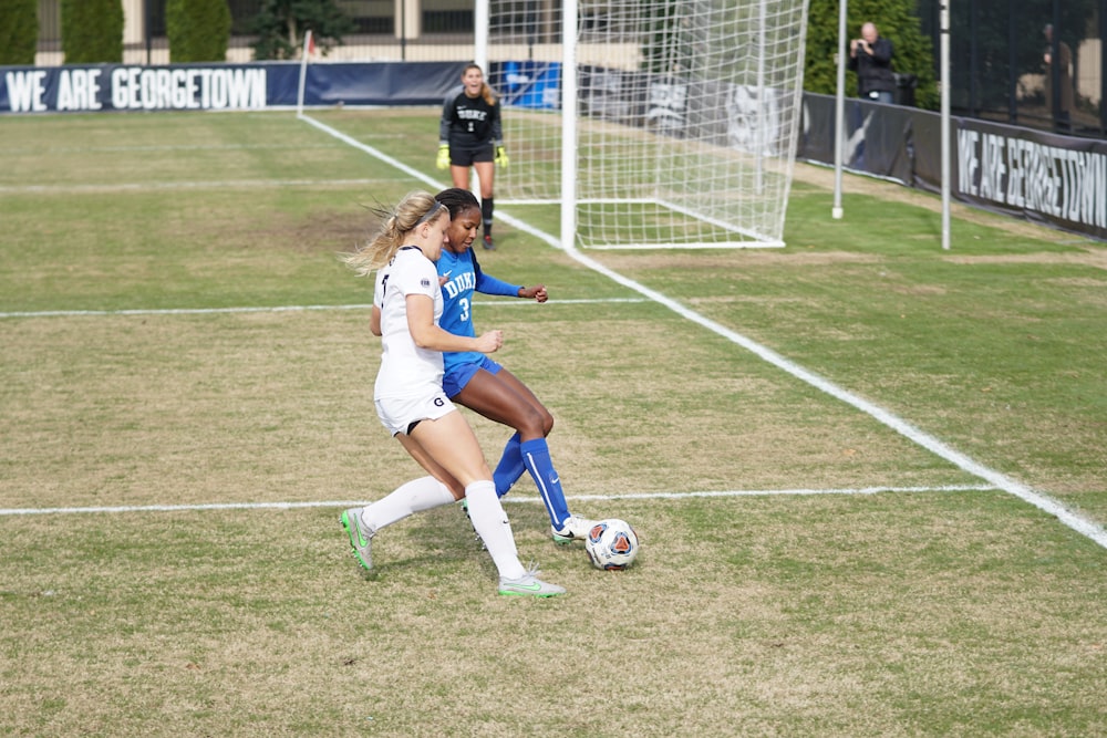 two girls playing soccer during daytime