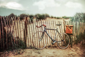 Vintage bicycle resting against a weathered wooden fence near the Adriatic coastline under soft evening light.