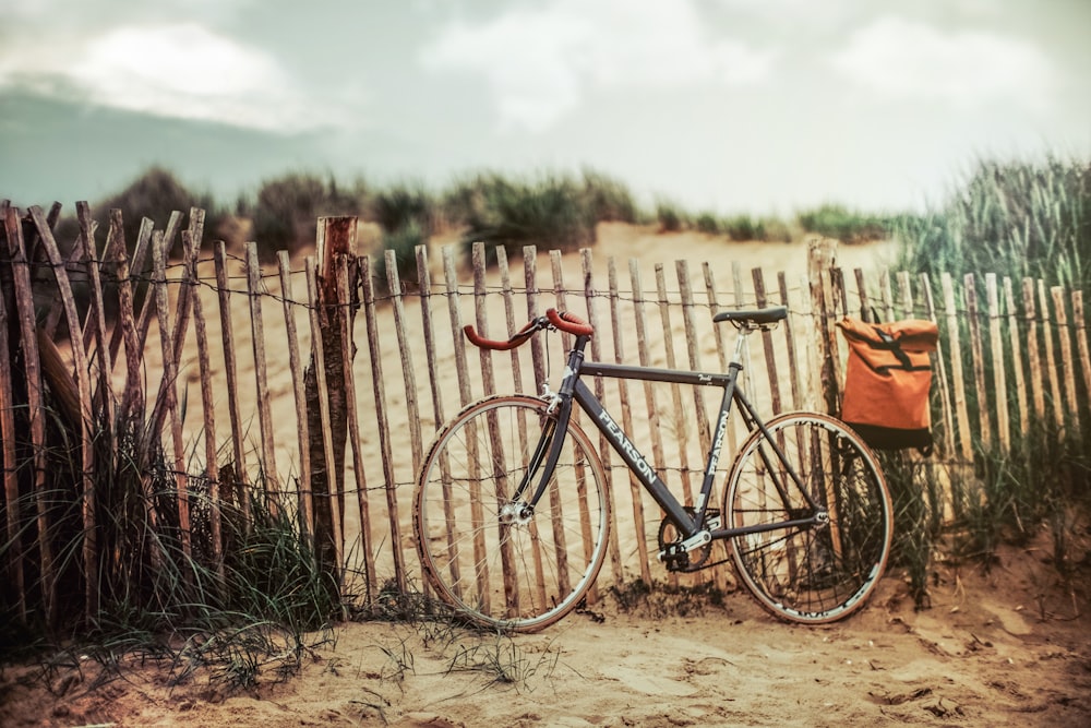 black road bike near brown wooden fence