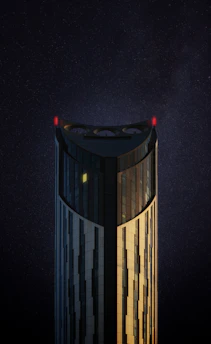 A sleek building facade glowing under carefully placed golden exterior lights against a deep navy night sky.