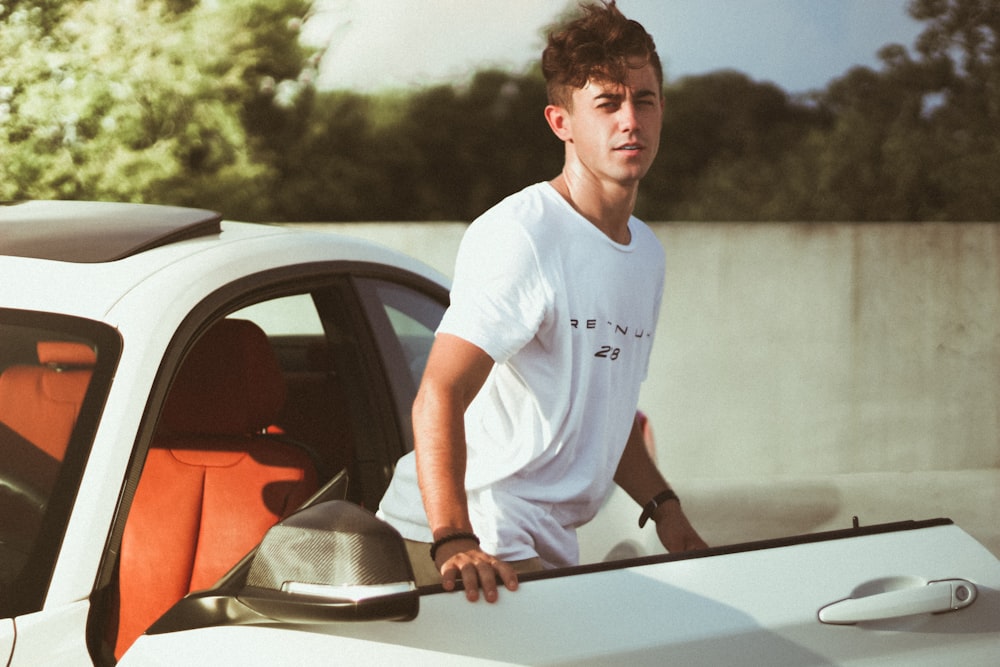 man standing beside white car