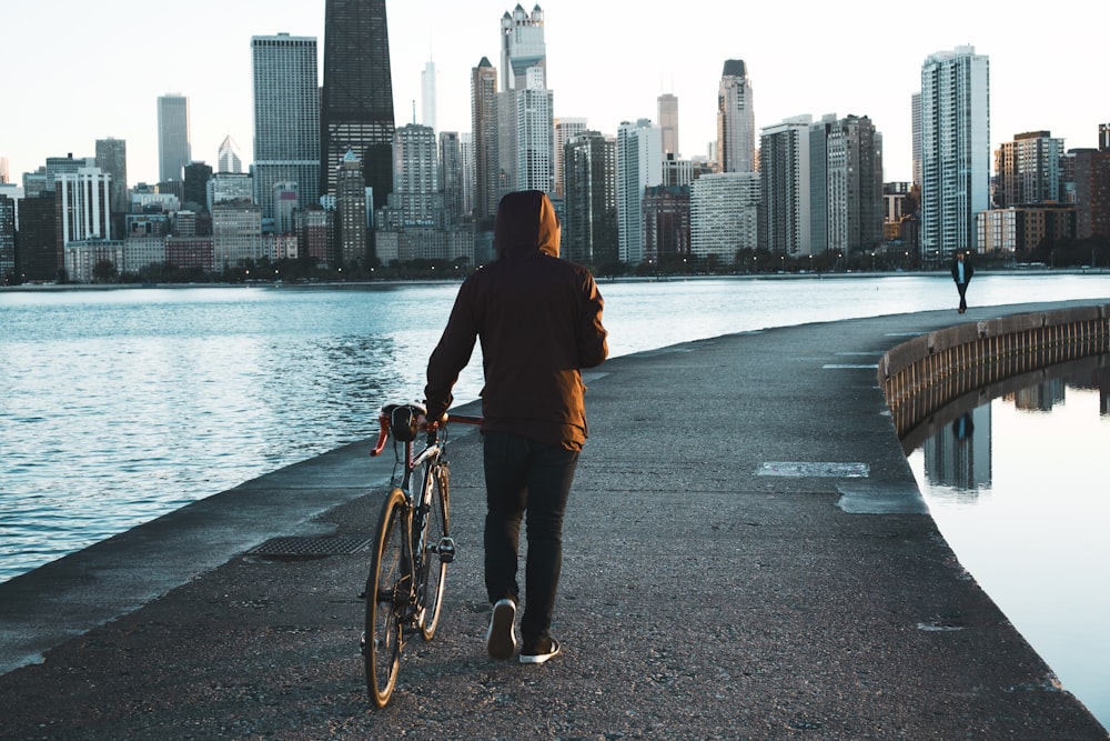 man walking on concrete walkway beside sea