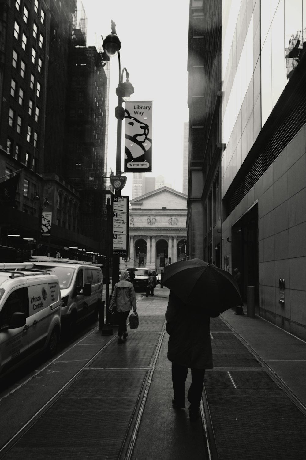grayscale photo of person under umbrella walking on roadside