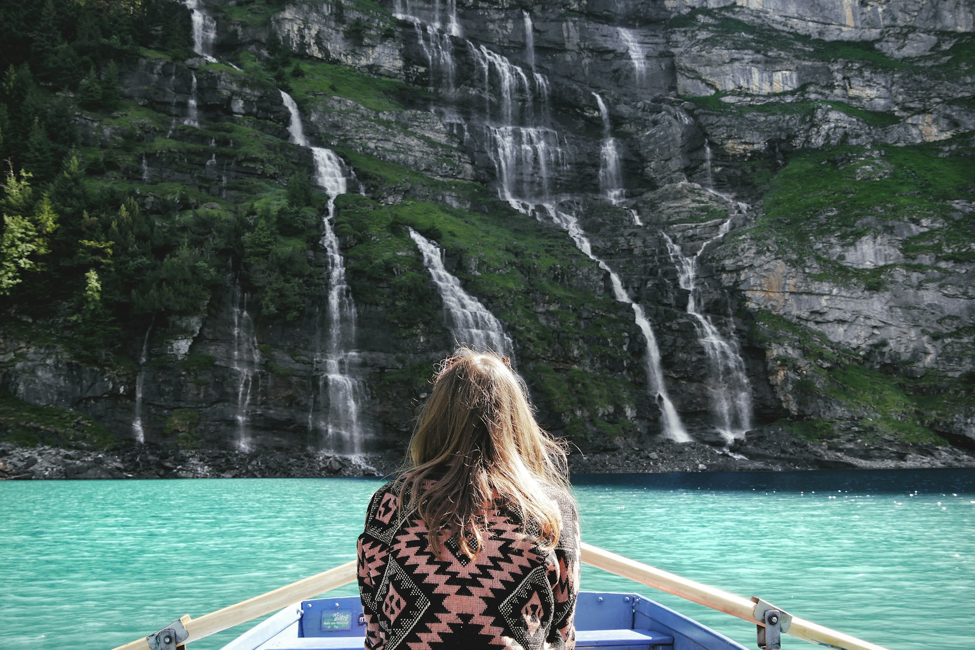 woman riding boat facing waterfalls