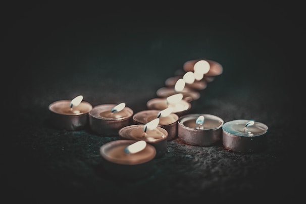 Close-up of neatly arranged tealight candles glowing softly on a wooden surface.