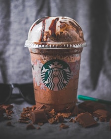 A colorful frap drink topped with whipped cream and chocolate drizzle.